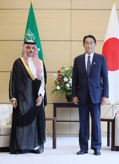 Faisal bin Farhan Al-Saud standing with Japanese Prime Minister Fumio Kishida in front of the Saudi and Japanese flags